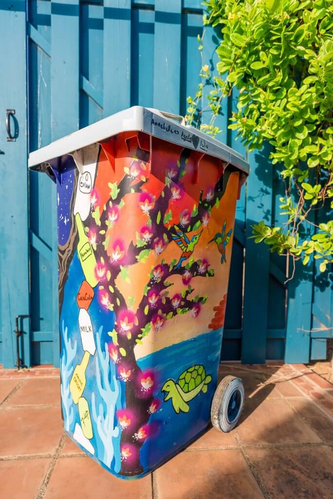 A trash bin with nature and litter painted on it